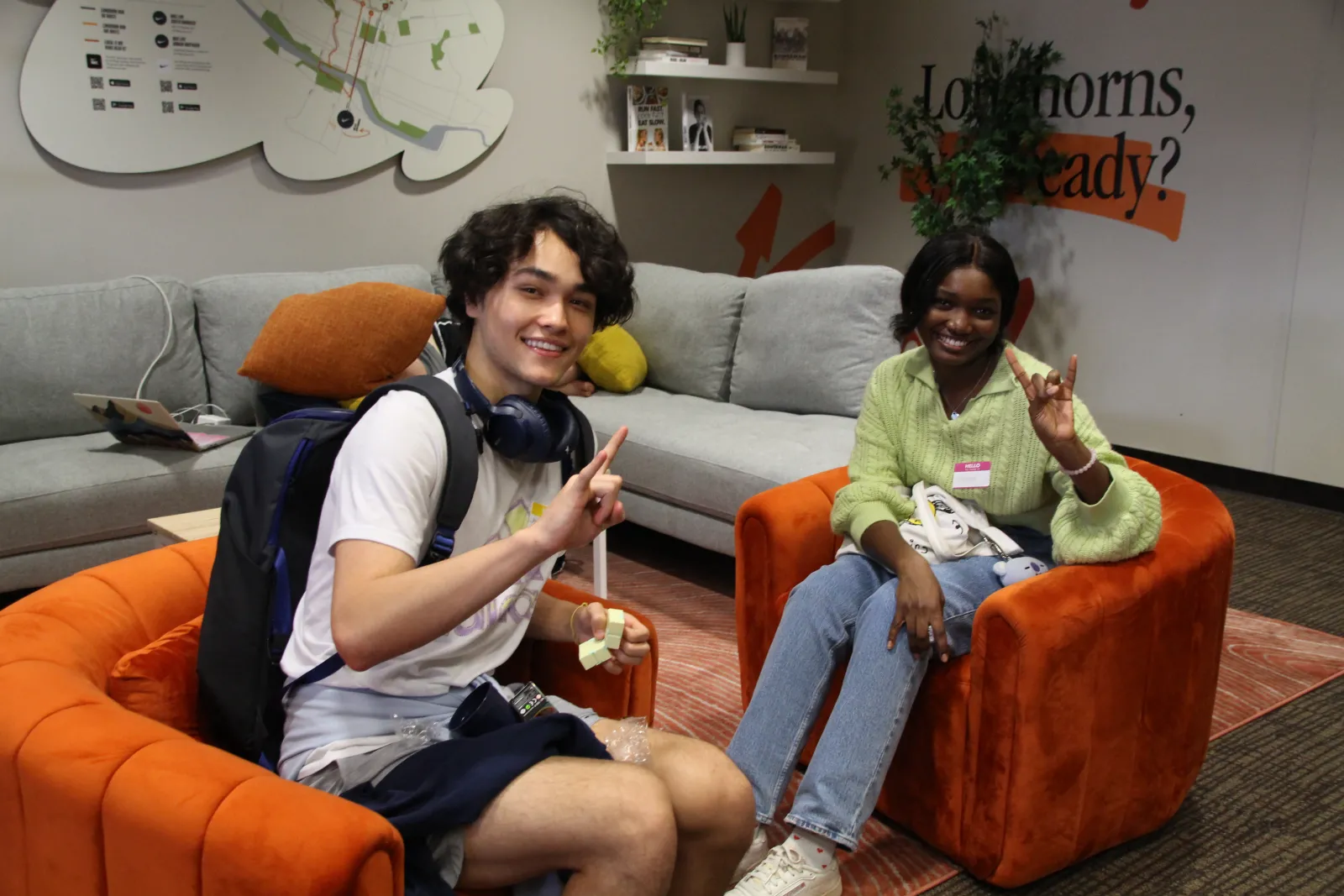 two students looking at the camera with a "hook'em" handsign