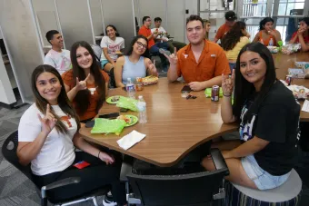 Students pose around a table at an RGV Familia event.