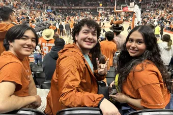 Three students pose at a UT basketball game
