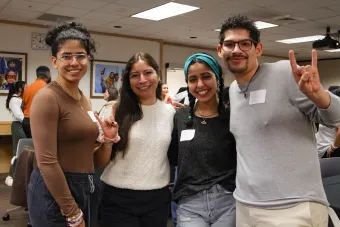 four students standing together. two students are holding up a hookem horns handsign
