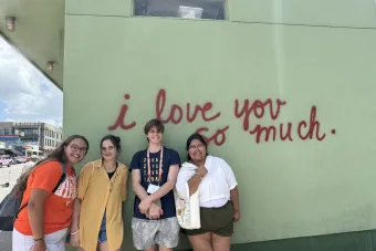 Four students pose in front of the I Love You So Much mural on South Congress.