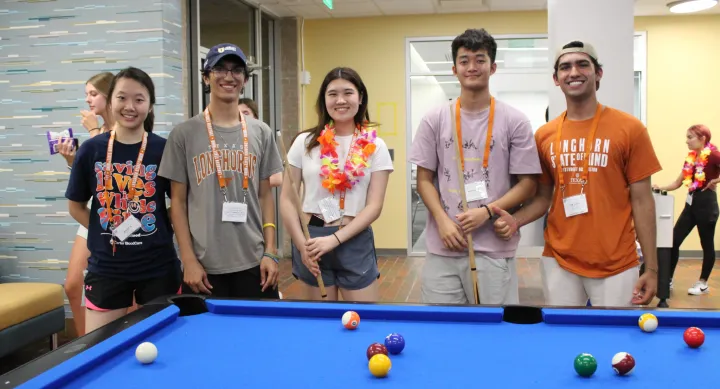 students posing together in front of a pool table