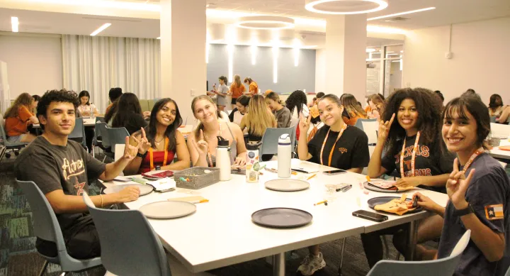 students posing together with a hookem horns