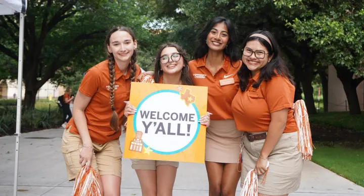Four orientation advisors holding a sign that reads Welcome Y'all at Longhorn Orientation