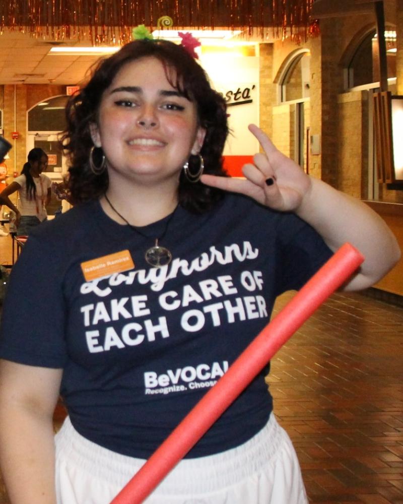 student holding up a hookem handsign
