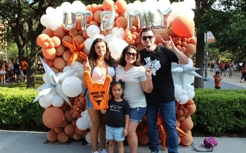 Family posing in front off balloons that say "UT Family"